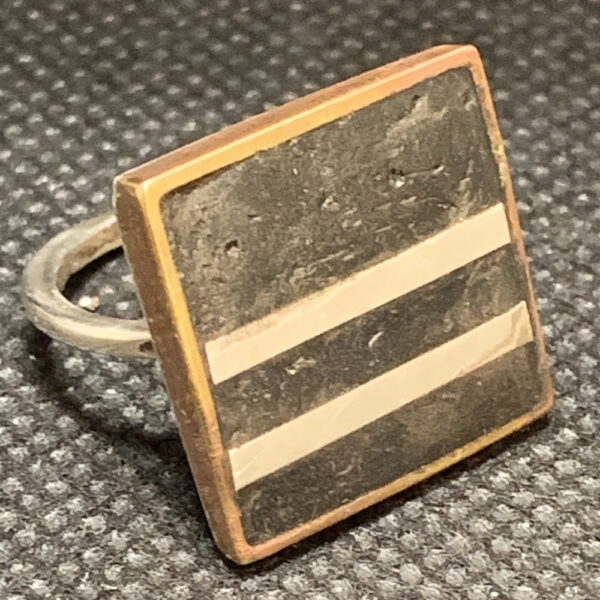 Mixed Metal. Brass frame/silver ring, charcoal-colored resin/